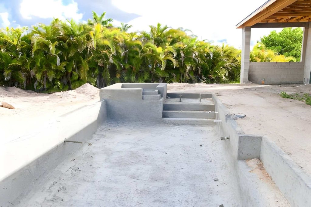 Pool remodeling Hobe Sound concrete pool under construction with steps, spa section, and tropical palm backdrop