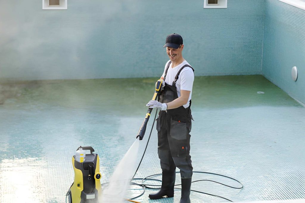 Pool cleaning service Port St Lucie professional using pressure washer to clean empty tiled swimming pool