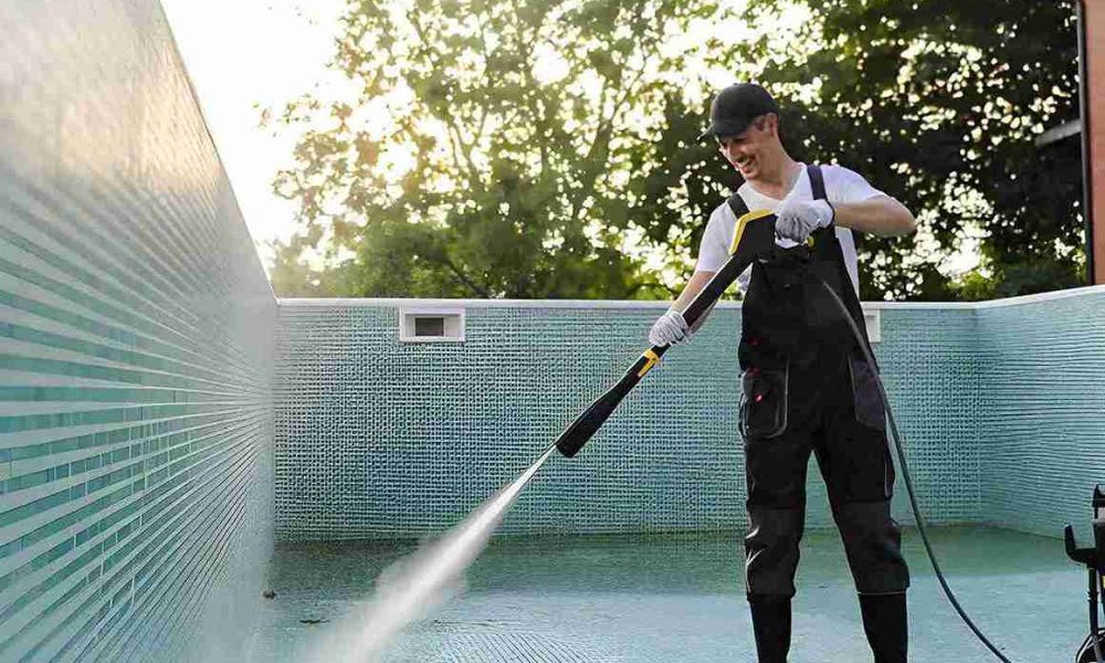 Professional technician pressure washing an empty swimming pool as part of a pool cleaning service Port St. Lucie maintenance program.