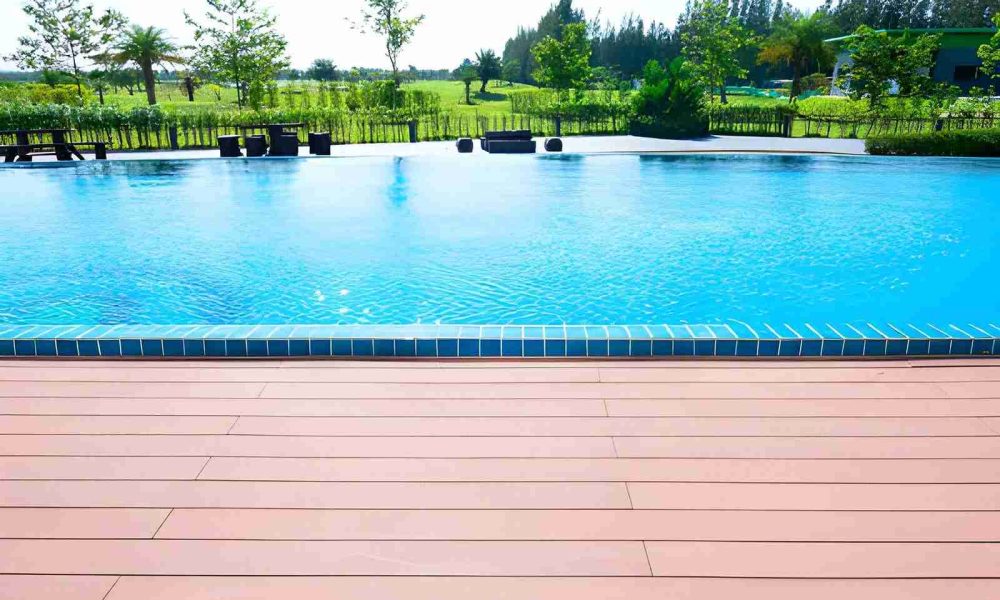 Pool maintenance Port St Lucie FL clear blue pool with tiled edge, wooden deck, and landscaped greenery