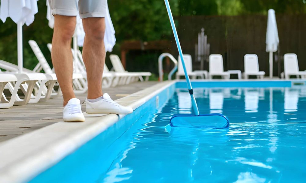 Pool maintenance Port St Lucie FL professional skimming pool water surface with long-handled net near lounge chairs