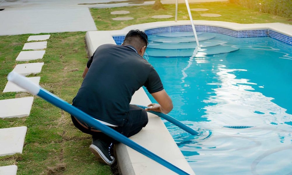 Pool maintenance South Florida worker vacuuming swimming pool with long pole and hose.