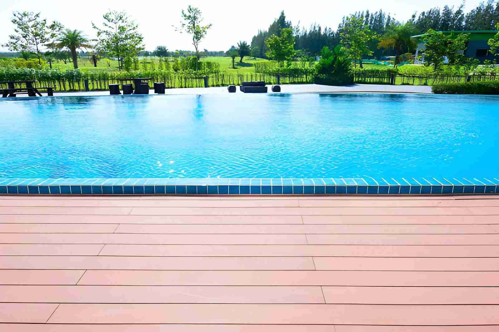 Pool maintenance Port St Lucie FL clear blue pool with tiled edge, wooden deck, and landscaped greenery