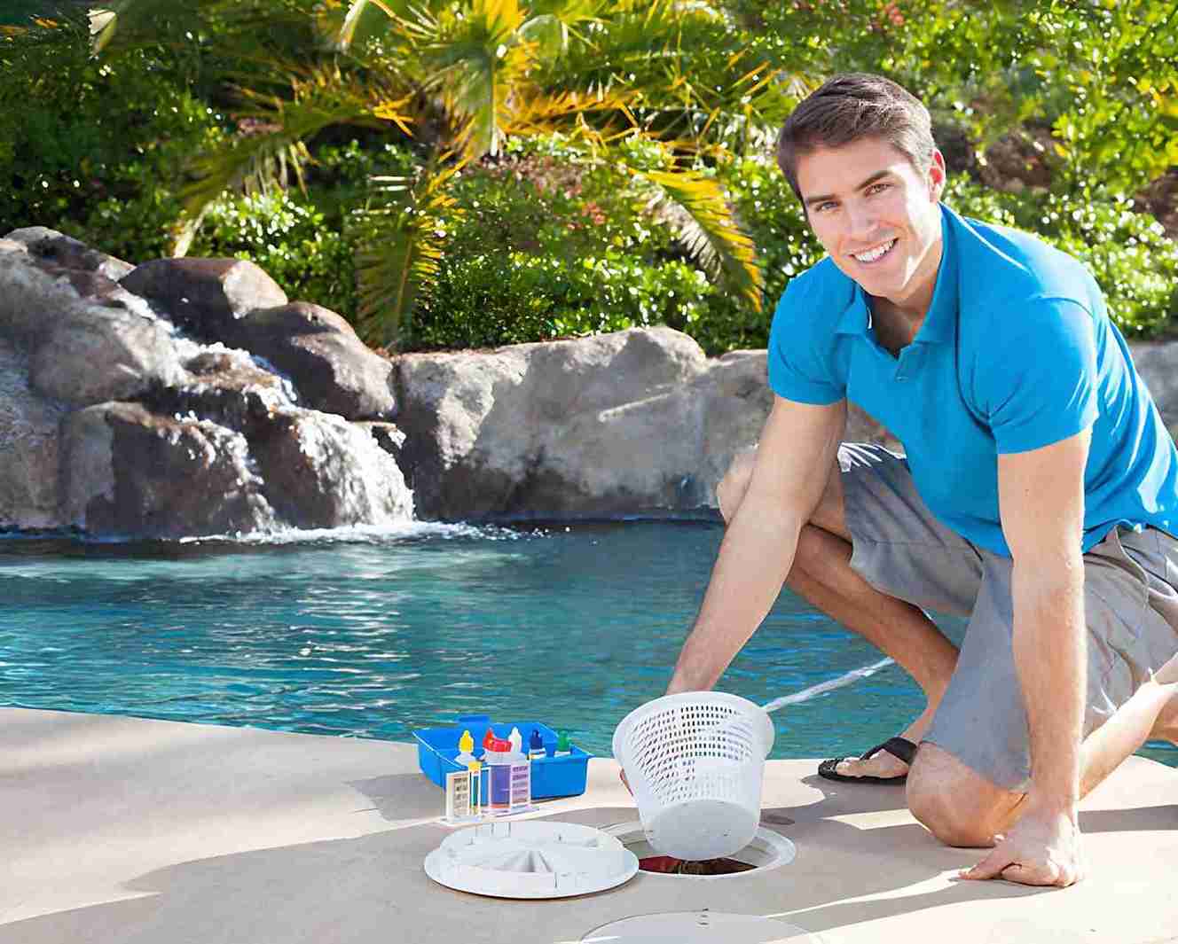 Pool cleaning and maintenance service Jensen Beach professional inspecting skimmer basket and testing water quality beside landscaped pool with waterfall
