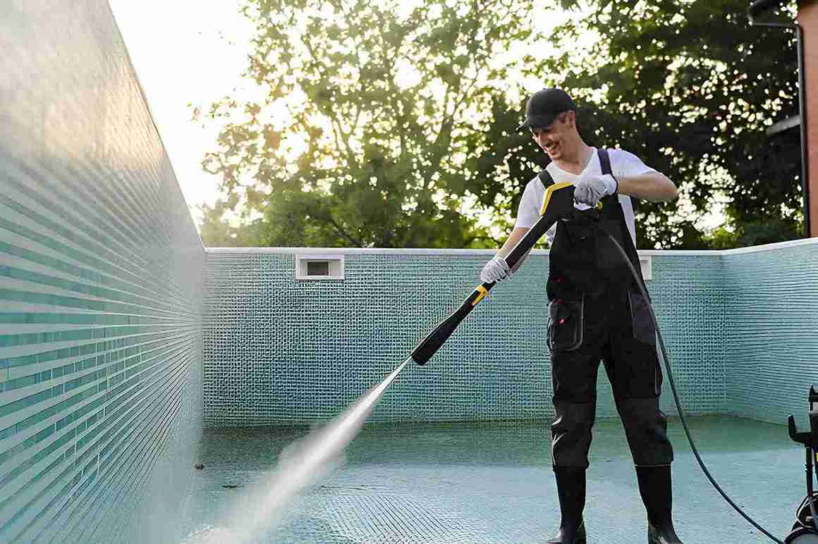 Professional technician pressure washing an empty swimming pool as part of a pool cleaning service Port St. Lucie maintenance program.